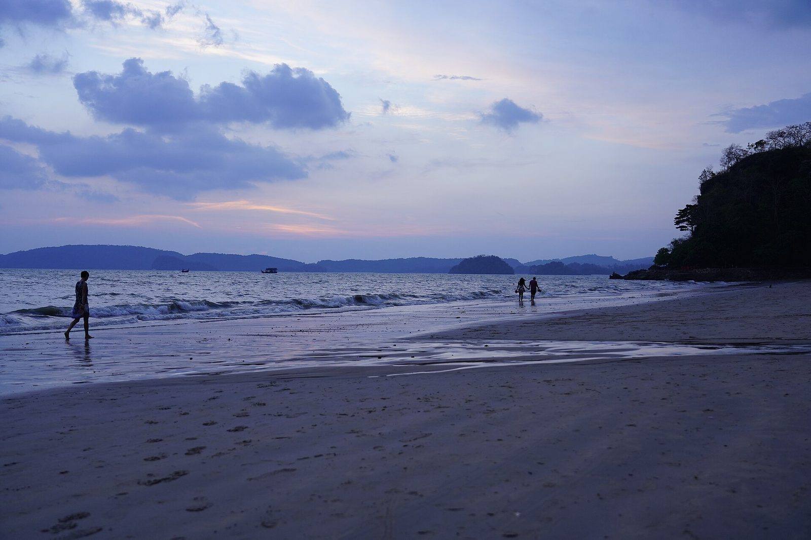 Ao Nang beach at dusk with people walking on the sand